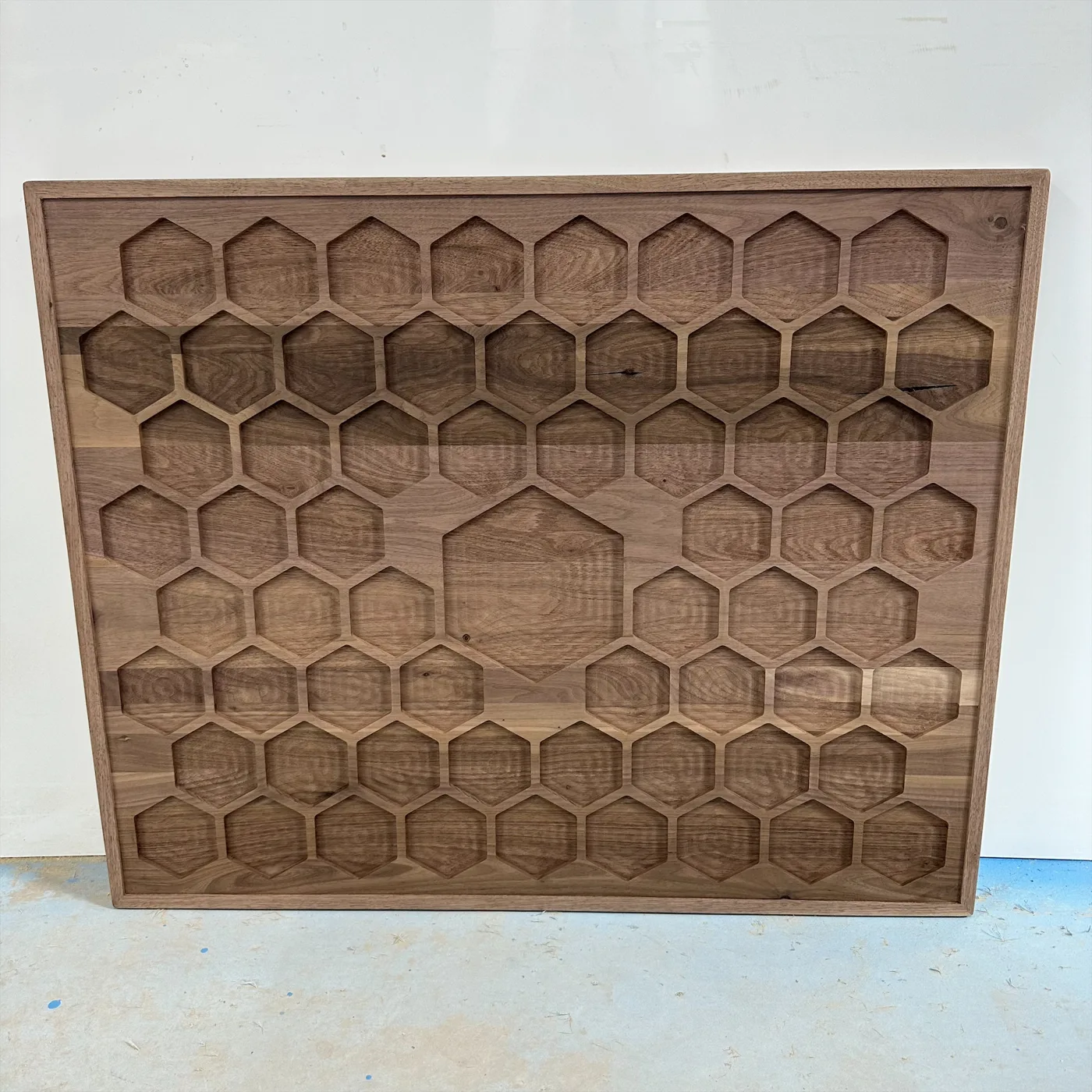 Detailed wood routing — A repeated honeycomb pocket pattern machined into a wood panel.